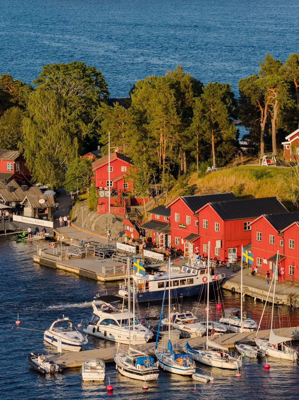 Skärgårdshamn med röda sjöbodar och båtar i kvällssol